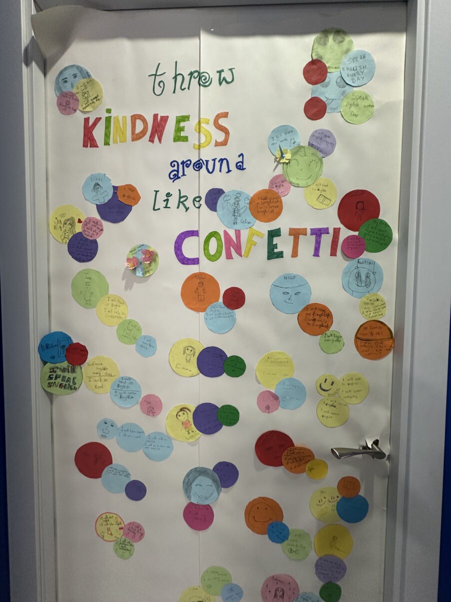 Puerta decorada con círculos de colores y la frase “Throw kindness around like confetti”